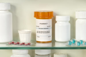 Prescription bottle on medicine cabinet glass shelf with medications.